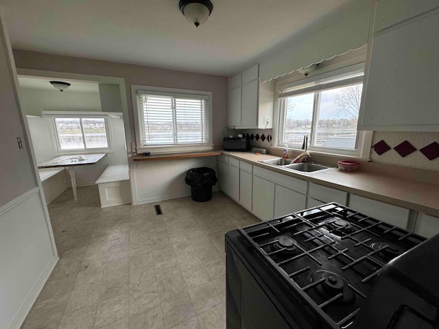 kitchen with sink, white cabinetry, a healthy amount of sunlight, and black appliances