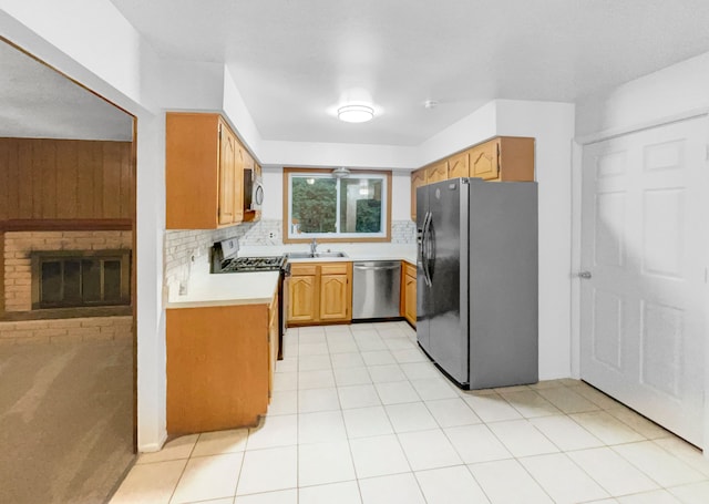 kitchen with a fireplace, stainless steel appliances, tasteful backsplash, and sink