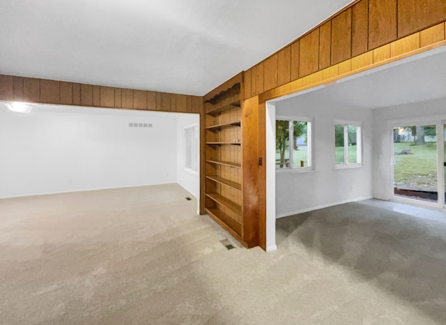 carpeted spare room with wooden walls