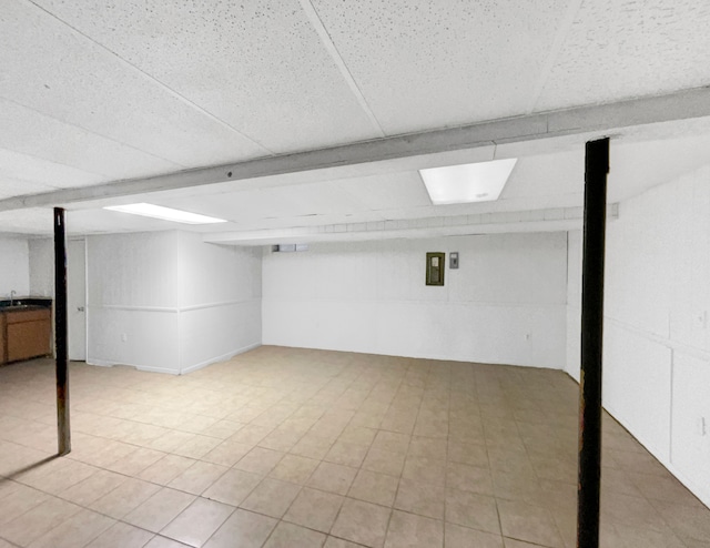 basement featuring a paneled ceiling and sink