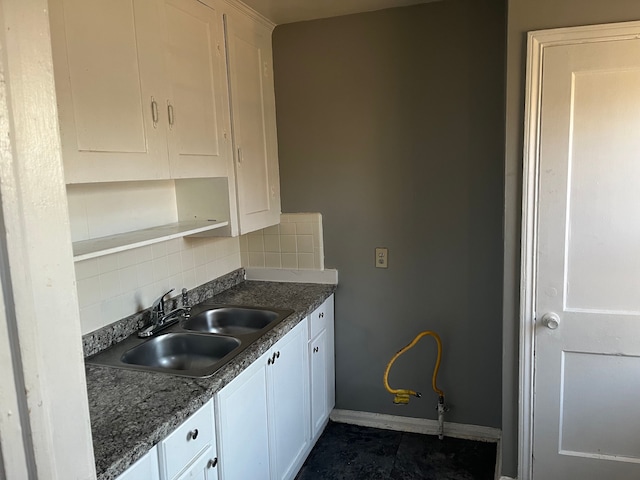 kitchen with decorative backsplash, dark tile patterned flooring, white cabinetry, and sink