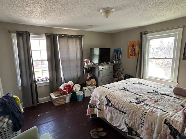 bedroom with dark hardwood / wood-style flooring, a textured ceiling, and multiple windows