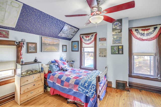 bedroom with ceiling fan, wood-type flooring, and multiple windows