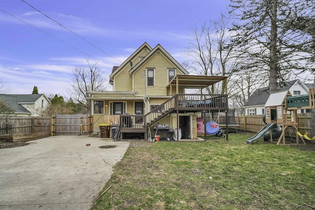 back of house featuring a lawn, a playground, and a wooden deck