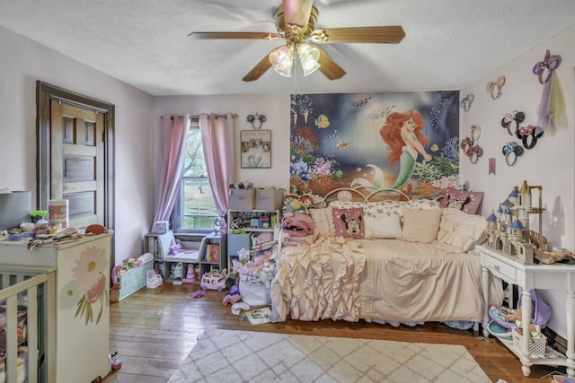 bedroom with hardwood / wood-style floors, ceiling fan, and a textured ceiling