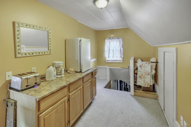 interior space featuring light colored carpet, lofted ceiling, and light brown cabinetry