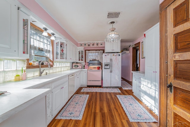 kitchen with white cabinetry, sink, decorative light fixtures, and white appliances