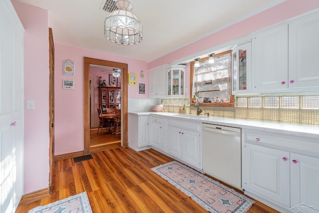 kitchen with pendant lighting, backsplash, white dishwasher, sink, and white cabinetry