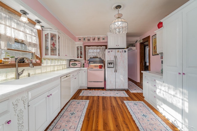 kitchen with pendant lighting, white appliances, dark wood-type flooring, white cabinets, and sink