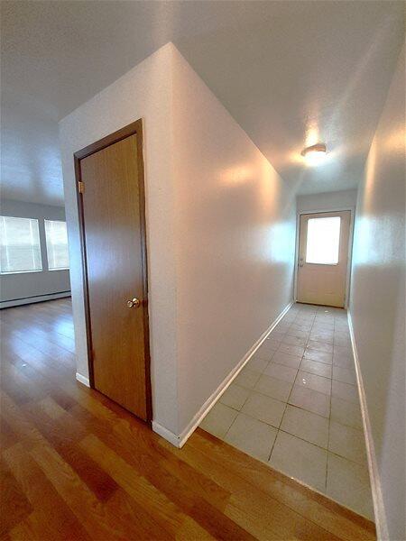 corridor featuring wood-type flooring and a baseboard radiator