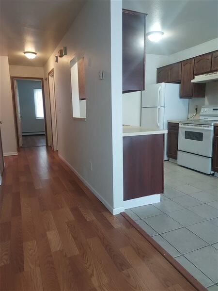 kitchen with light wood-type flooring, white appliances, and dark brown cabinetry