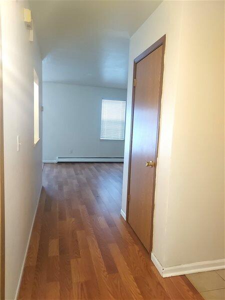 hallway featuring dark wood-type flooring and a baseboard radiator