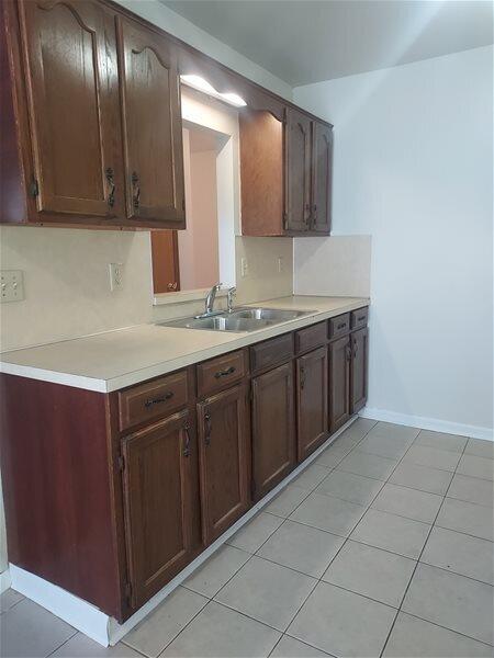 kitchen with dark brown cabinetry, sink, and light tile patterned floors