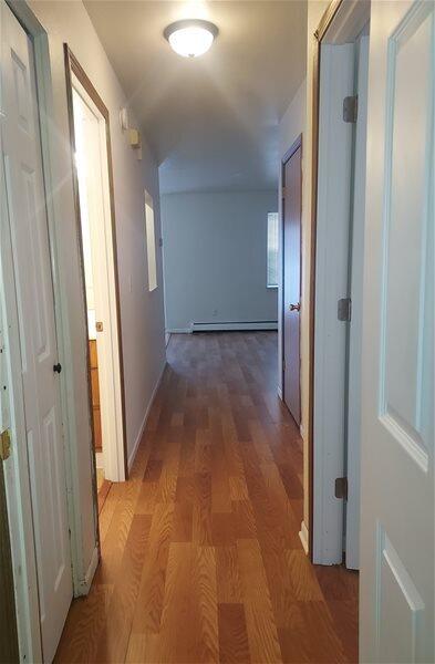 hallway featuring wood-type flooring and a baseboard heating unit