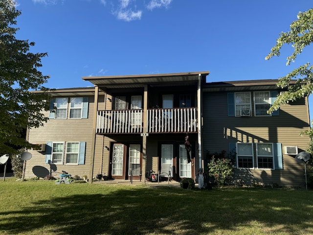 back of property with a lawn and a balcony