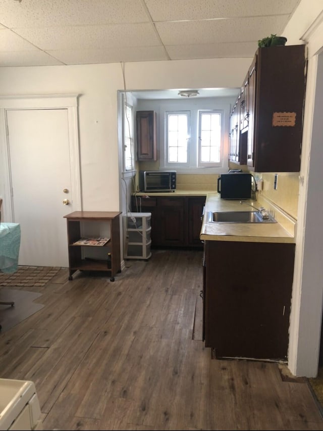 kitchen with a paneled ceiling, ceiling fan, dark brown cabinets, and dark wood-type flooring