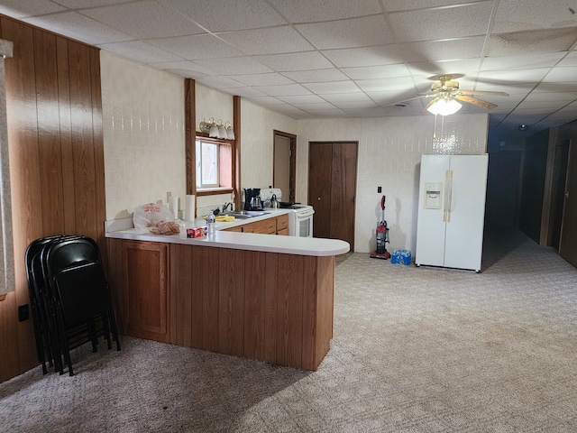 kitchen featuring a paneled ceiling, white appliances, sink, light colored carpet, and kitchen peninsula