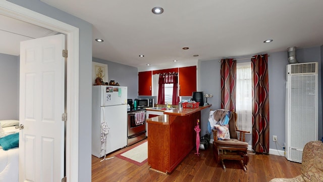 kitchen with a healthy amount of sunlight, wood-type flooring, kitchen peninsula, and stainless steel appliances