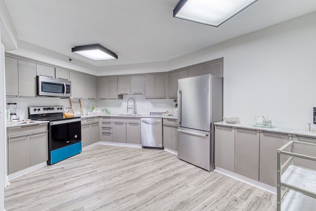 kitchen with gray cabinets, light hardwood / wood-style floors, sink, and stainless steel appliances