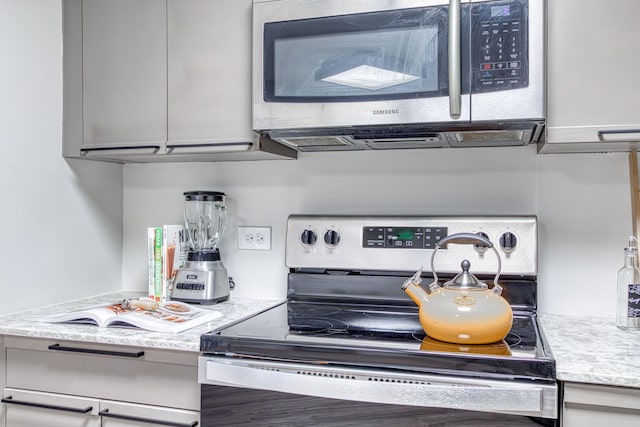 5000 Town Ctr Unit 2205, Southfield, MI 48075 - kitchen with stainless steel appliances, gray cabinetry, and light stone countertops