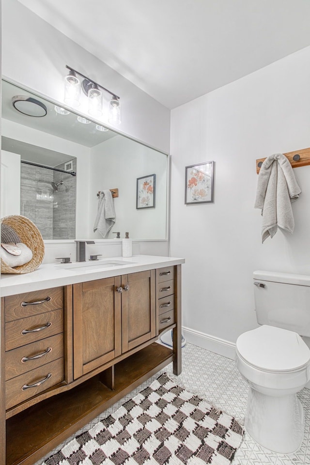 bathroom featuring tile patterned flooring, vanity, toilet, and tiled shower