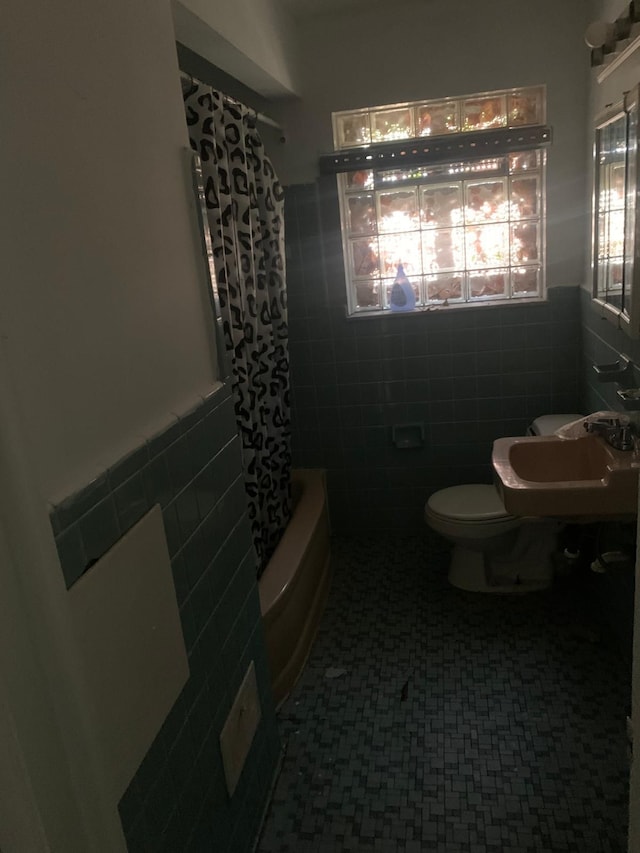 full bathroom featuring toilet, sink, tile walls, and shower / tub combo with curtain