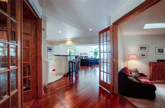 hall with french doors, hardwood / wood-style flooring, and a skylight