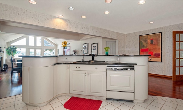 kitchen with sink, dishwasher, light hardwood / wood-style flooring, lofted ceiling, and white cabinets