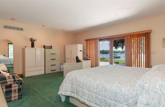 bedroom featuring access to exterior, a water view, and dark colored carpet