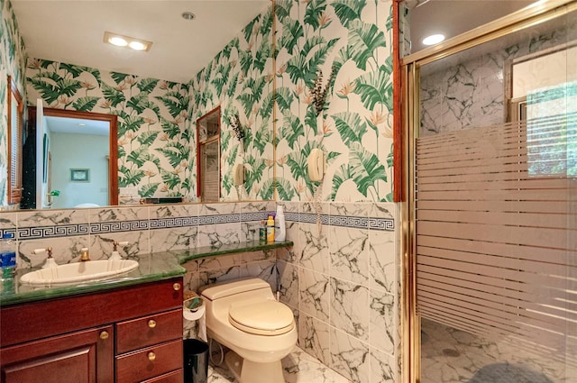 bathroom with vanity, a shower with door, toilet, and tile walls