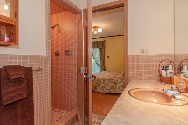 bathroom featuring tile patterned flooring, a tile shower, vanity, and tile walls