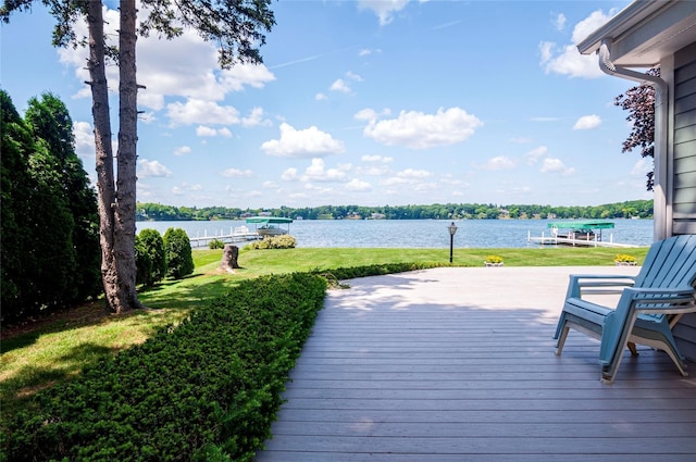 wooden terrace featuring a boat dock, a water view, and a yard