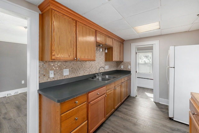 kitchen with white fridge, tasteful backsplash, dark wood-type flooring, and sink