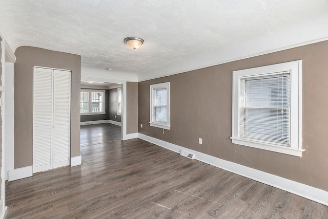 spare room featuring dark hardwood / wood-style flooring and a textured ceiling