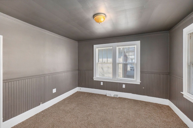 unfurnished room with carpet flooring, wooden walls, and ornamental molding