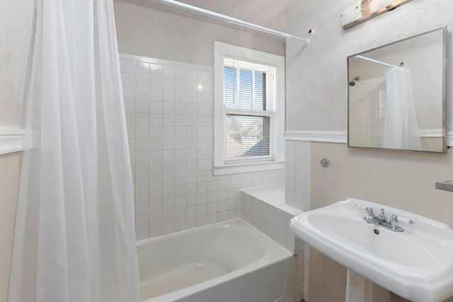 bathroom featuring shower / bathtub combination with curtain and sink