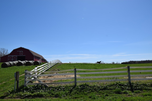 view of gate featuring a yard, a rural view, and an outdoor structure