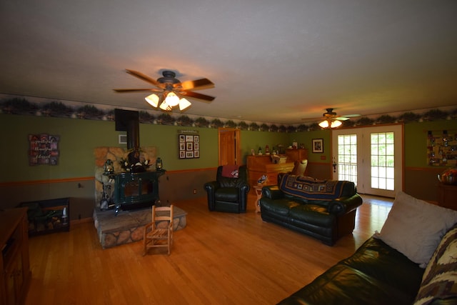 living room featuring a wood stove, ceiling fan, and hardwood / wood-style flooring