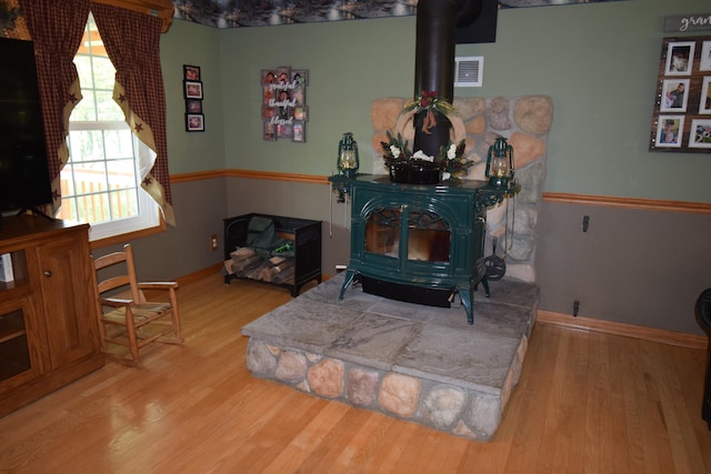 interior space with a wood stove and hardwood / wood-style flooring