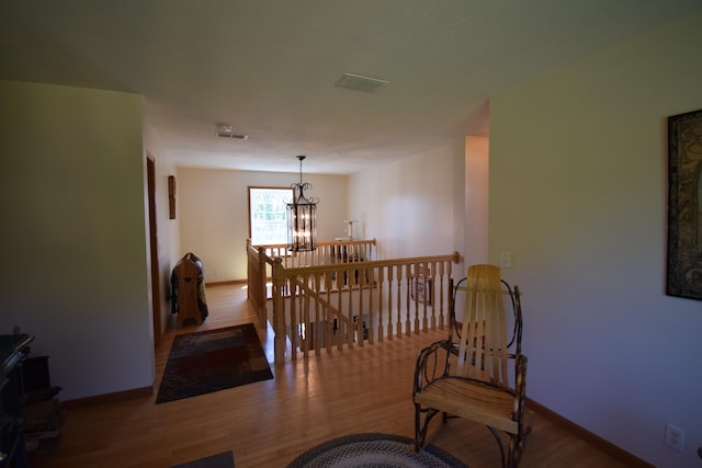 corridor with a notable chandelier and hardwood / wood-style flooring