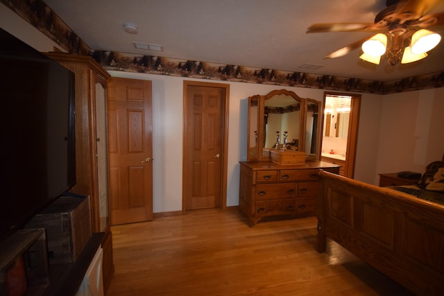 bedroom featuring ceiling fan, light hardwood / wood-style floors, and ensuite bath