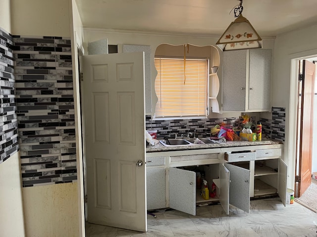 kitchen with white cabinetry, decorative backsplash, sink, and pendant lighting