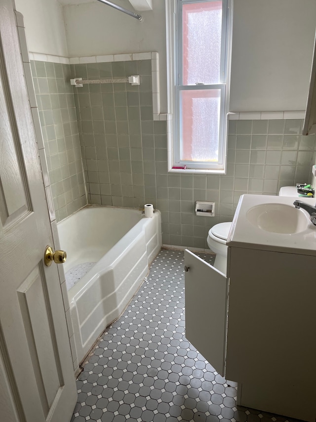 full bathroom with shower / bathing tub combination, vanity, tile patterned floors, toilet, and tile walls