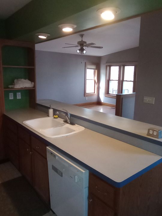 kitchen featuring kitchen peninsula, white dishwasher, ceiling fan, sink, and lofted ceiling