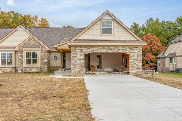 12258 Tullymore Dr, Stanwood, MI 49346 - craftsman-style home featuring stone siding, driveway, a garage, and roof with shingles