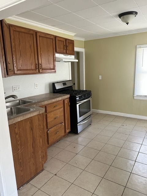 kitchen with stainless steel gas stove, light tile patterned floors, ornamental molding, and sink