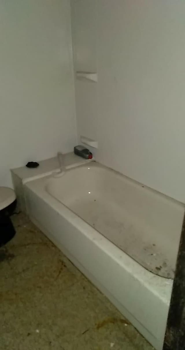 bathroom with a washtub and toilet