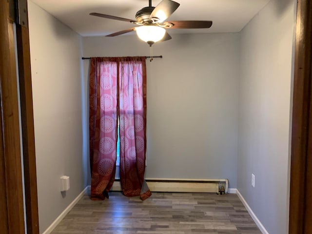 unfurnished room featuring ceiling fan, wood-type flooring, and a baseboard radiator