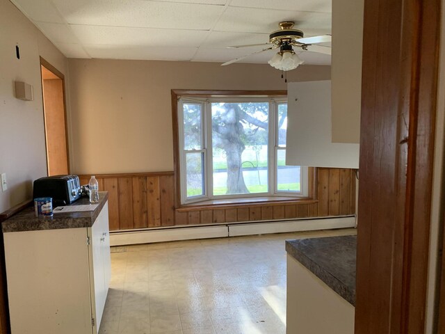 412 N Darling Ave, Fremont, MI 49412 - unfurnished dining area with a wainscoted wall, a baseboard heating unit, wood walls, and a ceiling fan