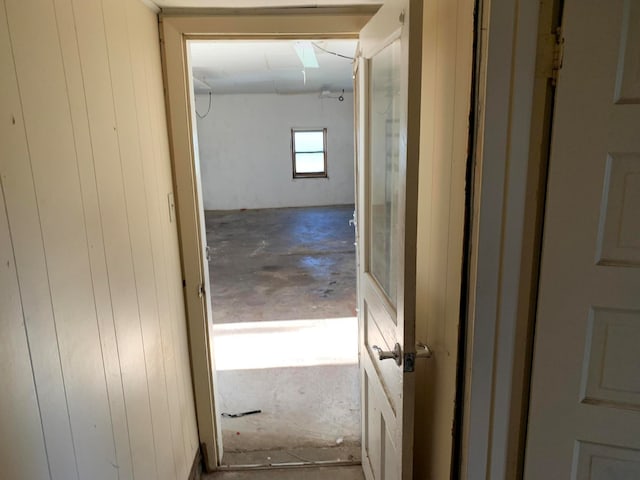 hall featuring concrete floors and wooden walls